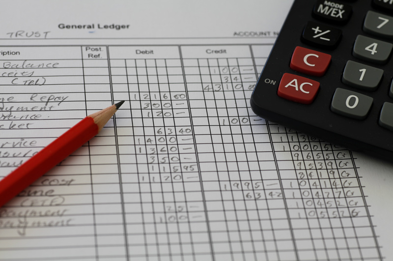 Bookkeeping paper with debit and credit numbers with pencil and calculator