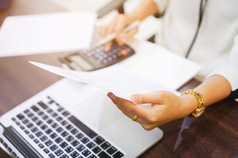 close up of a women checking a statement with laptop and calculator out