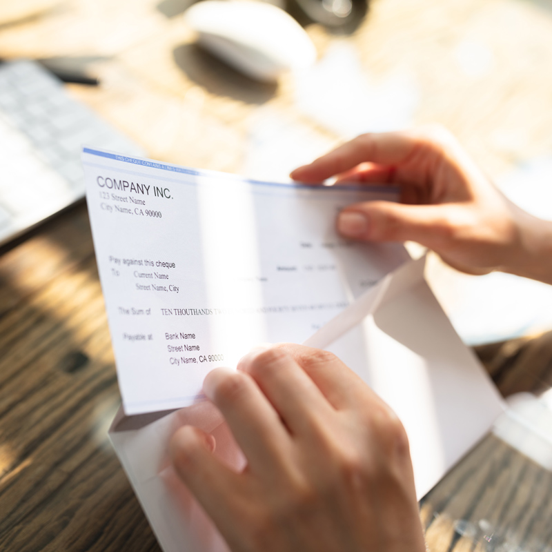 Person opening their pay slip in front of a computer