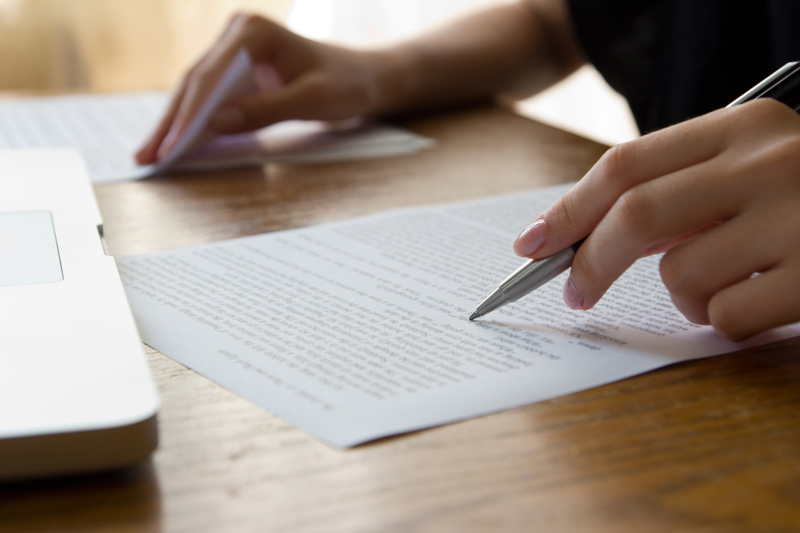 Person proof reading a letter or document in front of a computer