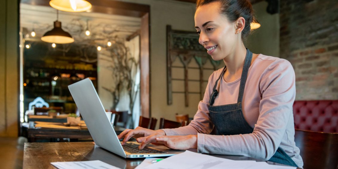 Business owner working at a restaurant doing the bookkeeping using her laptop virtual assistant