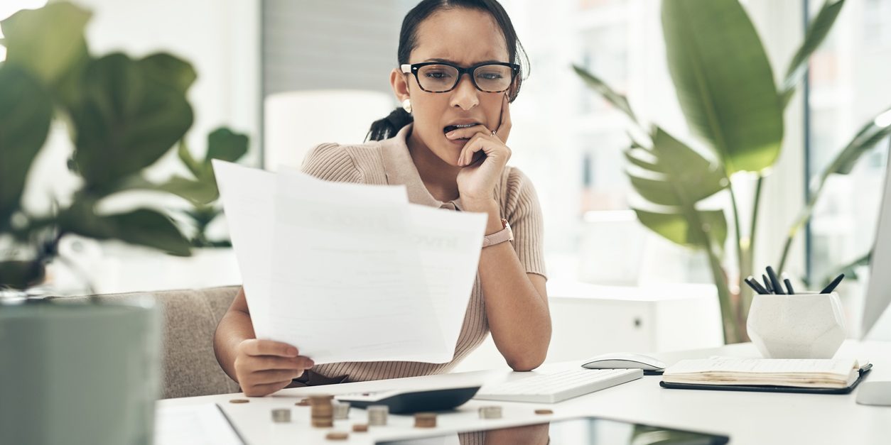 Shot of a young businesswoman looking stressed out while calculating finances in an office errors